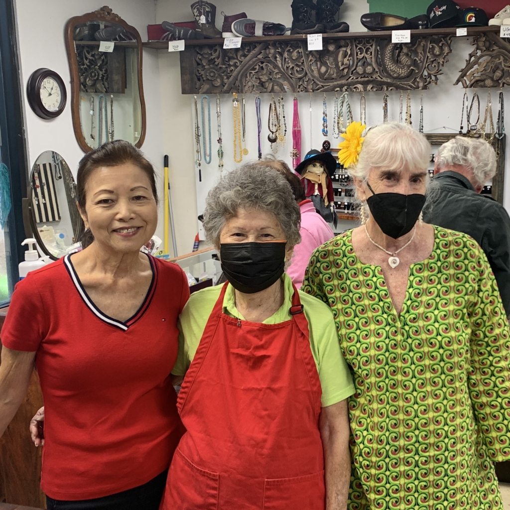 three women Joan Carol Georgia volunteer in the thrift shop smile for photo