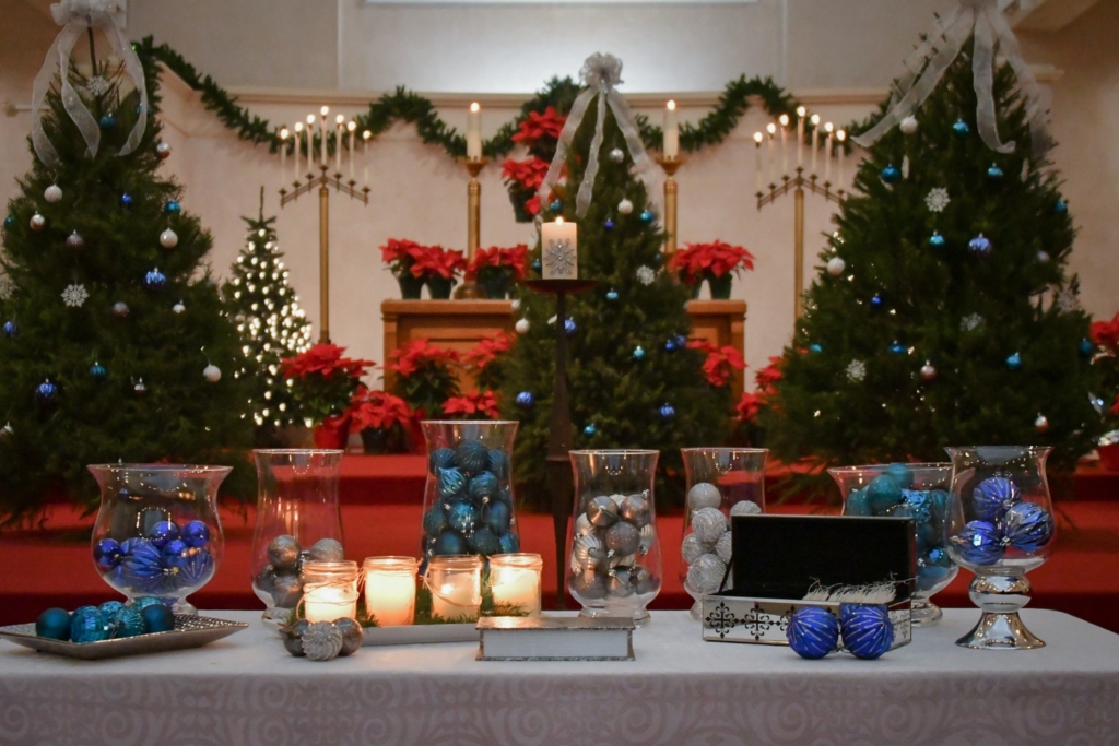 three christmas trees, ornaments in vases, lit candles in sanctuary for Blue Christmas service in 2022 at Central Union Church