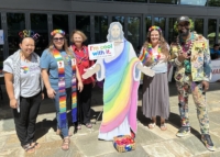 group photo of five people with lifesize cutout of jesus with rainbow colors at national coming out day fair